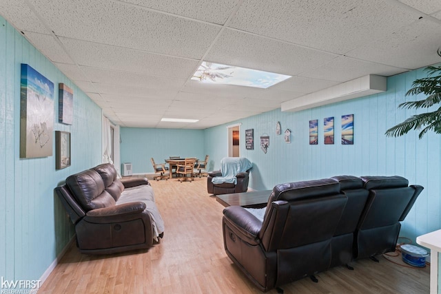 living room with a drop ceiling and wood-type flooring