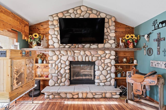 living room featuring lofted ceiling, a stone fireplace, and wood-type flooring