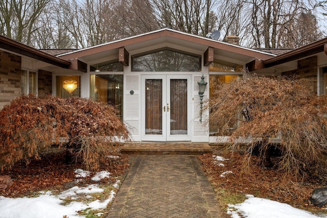 snow covered property entrance featuring french doors