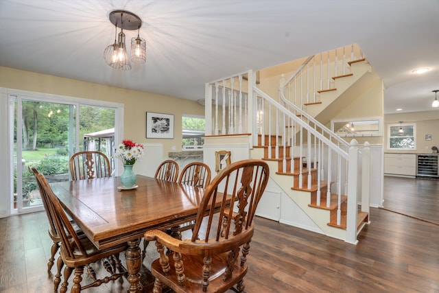 dining space with a notable chandelier, beverage cooler, and dark hardwood / wood-style flooring