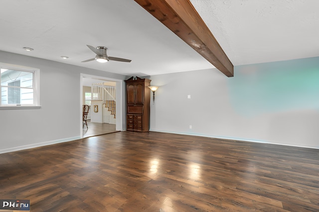 unfurnished living room featuring beamed ceiling, dark hardwood / wood-style floors, and ceiling fan