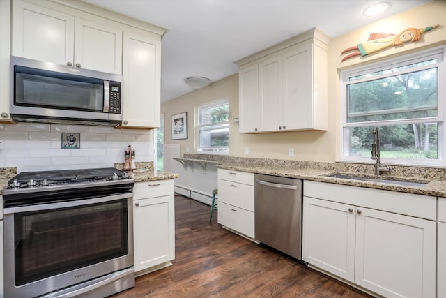 kitchen featuring stainless steel appliances, light stone countertops, sink, and backsplash