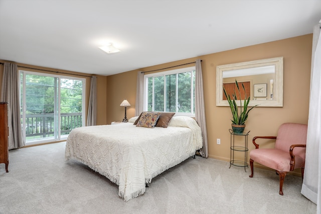 bedroom with multiple windows, access to outside, and light colored carpet