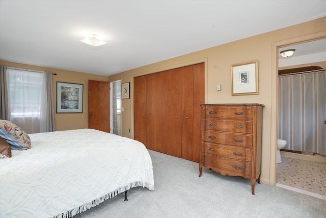 carpeted bedroom with a closet and ensuite bathroom