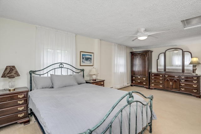 bedroom with ceiling fan, light colored carpet, and a textured ceiling