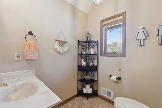 bathroom featuring vanity, vaulted ceiling, tile patterned floors, and toilet