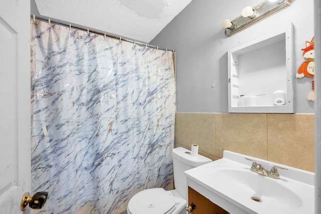 bathroom with tile walls, vanity, a textured ceiling, toilet, and walk in shower