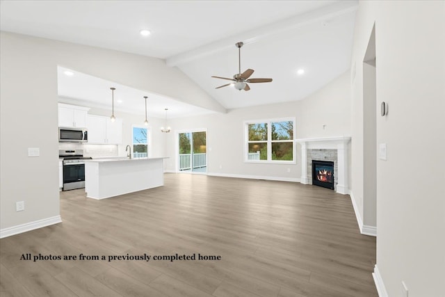 unfurnished living room with high vaulted ceiling, sink, ceiling fan, light hardwood / wood-style floors, and beam ceiling