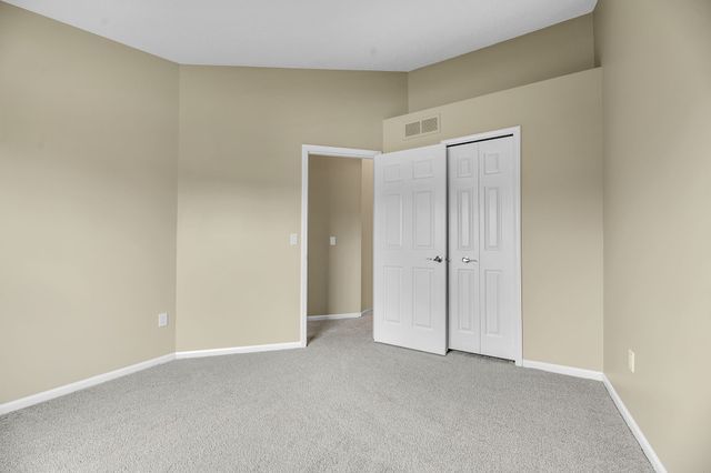 unfurnished bedroom with a closet, vaulted ceiling, and light carpet