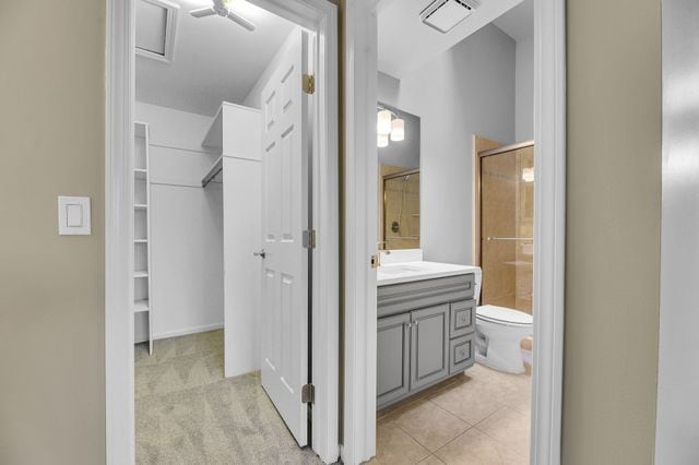 bathroom with vanity, toilet, a shower with shower door, and tile patterned flooring