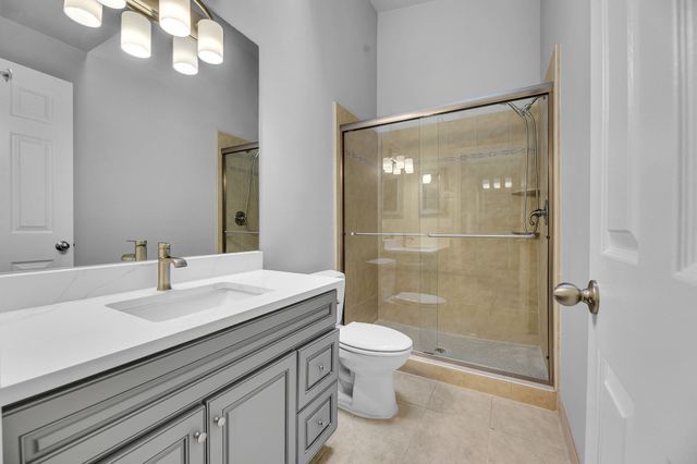 bathroom featuring vanity, toilet, an enclosed shower, and tile patterned flooring