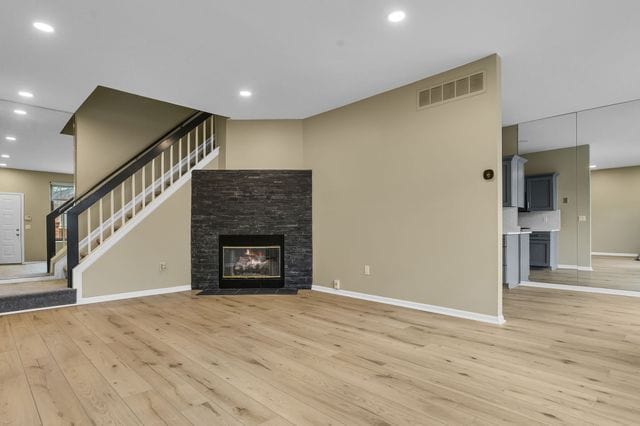 unfurnished living room with a stone fireplace and light hardwood / wood-style flooring