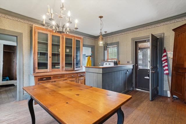 dining room with crown molding, dark wood-type flooring, and an inviting chandelier