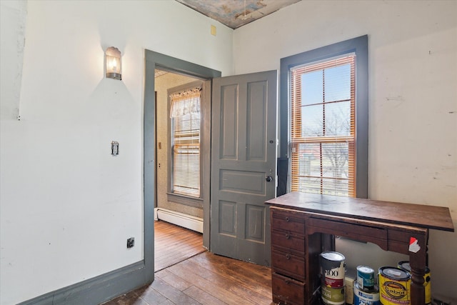 office area with a baseboard heating unit and hardwood / wood-style flooring