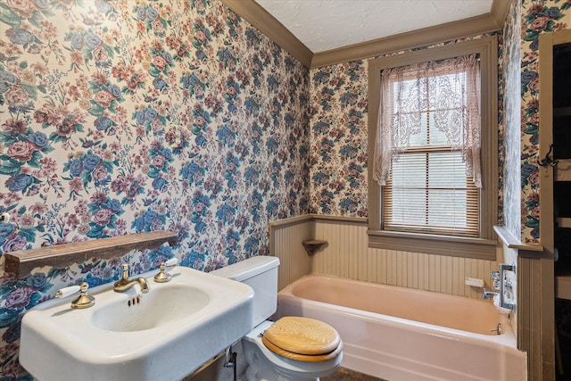 bathroom with a tub to relax in, toilet, sink, and a textured ceiling