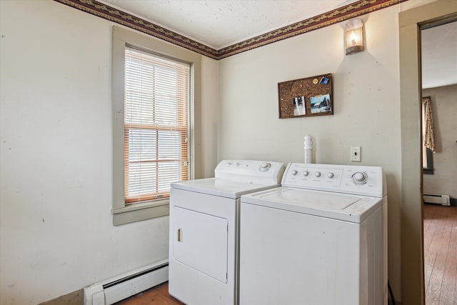 laundry area with a baseboard heating unit, washer and clothes dryer, and light hardwood / wood-style floors