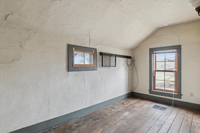 spare room featuring wood-type flooring and vaulted ceiling