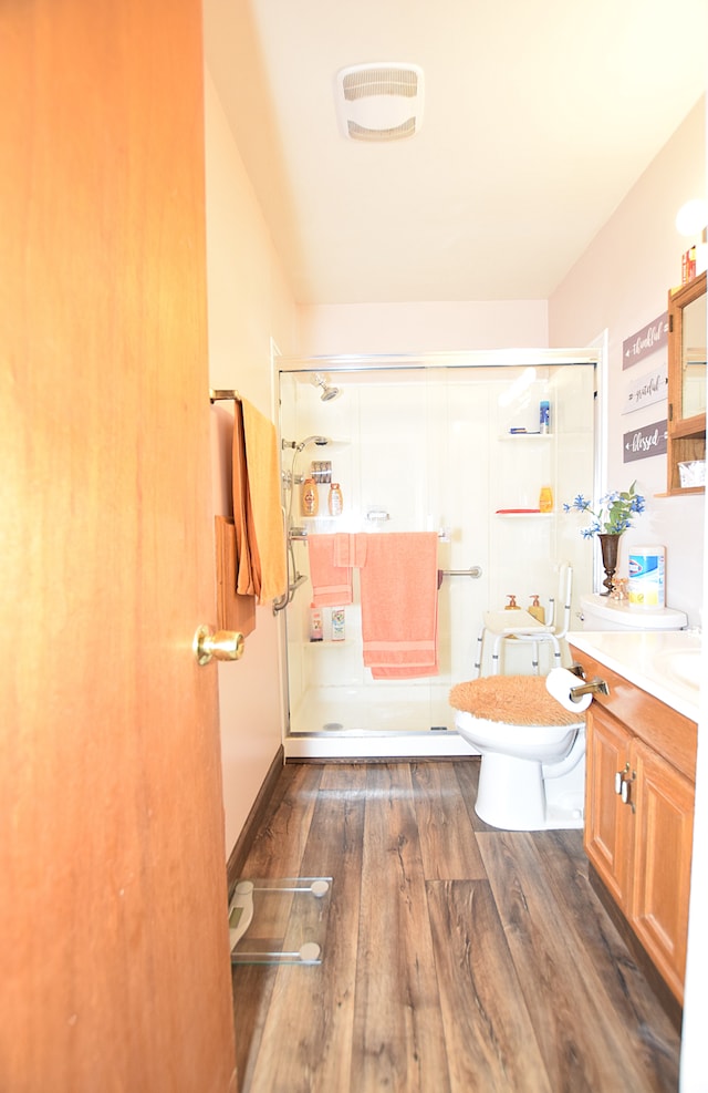 bathroom with walk in shower, vanity, toilet, and hardwood / wood-style floors