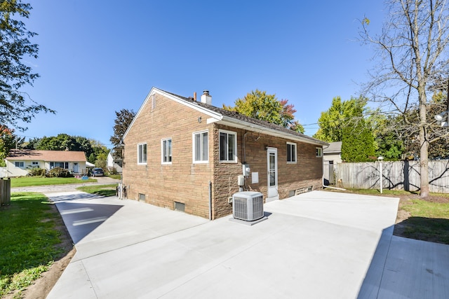 view of side of property with cooling unit, a patio area, fence, and a chimney