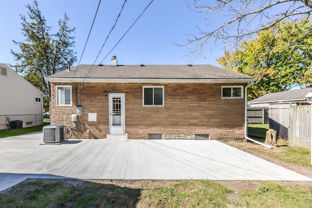 rear view of property featuring stone siding, a patio area, fence, and central AC