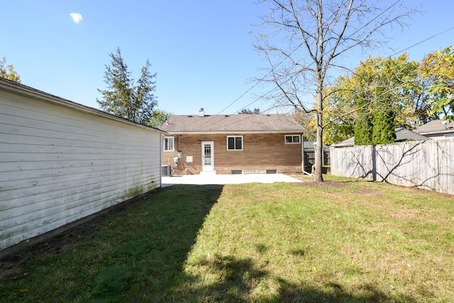 rear view of property featuring central air condition unit, brick siding, fence, a lawn, and a patio area