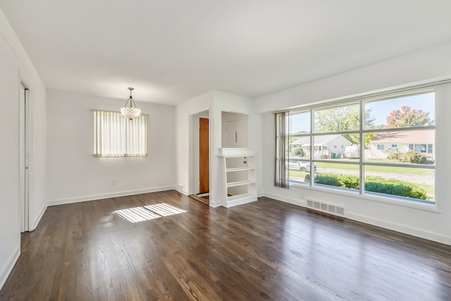 unfurnished living room featuring dark wood-type flooring, visible vents, baseboards, and an inviting chandelier