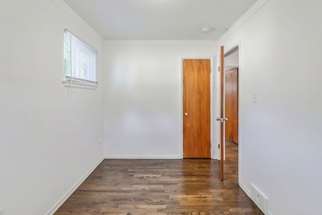 empty room with wood finished floors, visible vents, and baseboards