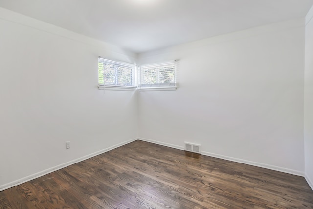 empty room with baseboards, visible vents, and dark wood-type flooring