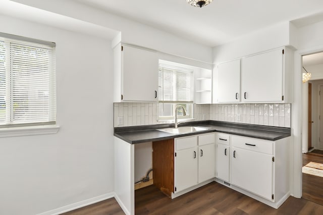 kitchen featuring tasteful backsplash, dark countertops, a sink, and dark wood-style floors