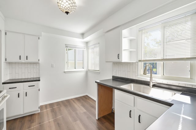 kitchen with dark countertops, dark wood-style floors, white cabinetry, and a sink