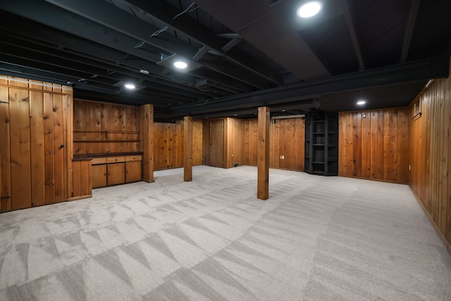 finished basement featuring light carpet and wooden walls