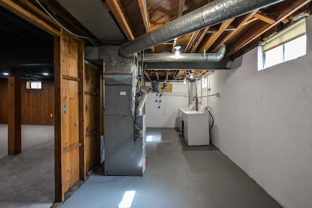 basement with heating unit, wooden walls, and separate washer and dryer