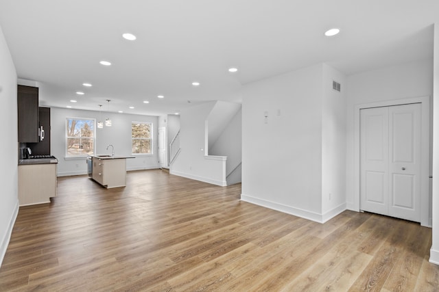 unfurnished living room with sink and light hardwood / wood-style flooring