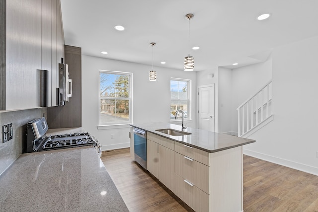 kitchen featuring pendant lighting, sink, range, light stone counters, and stainless steel dishwasher