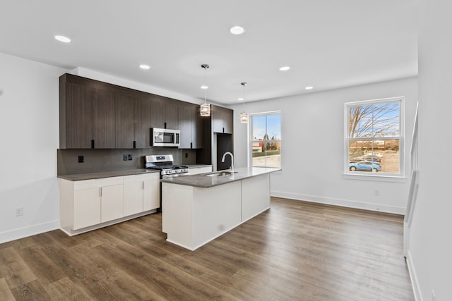 kitchen featuring decorative light fixtures, an island with sink, sink, dark brown cabinetry, and stainless steel appliances