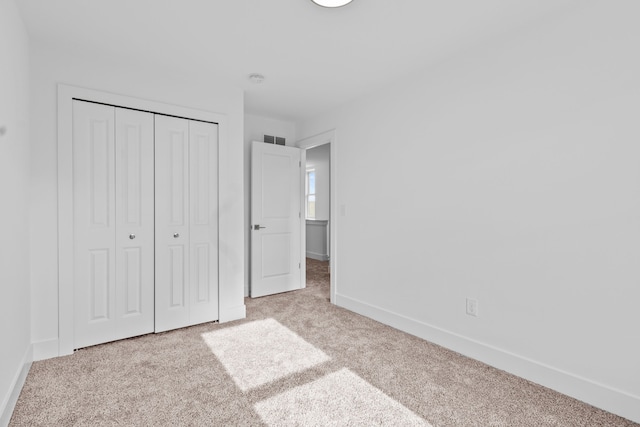 unfurnished bedroom featuring light carpet and a closet