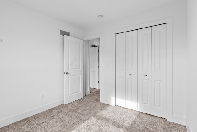 unfurnished bedroom featuring a closet and light carpet