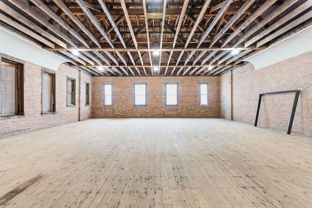 basement featuring wood-type flooring and brick wall