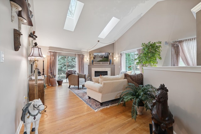 living room with a healthy amount of sunlight, a skylight, light wood-type flooring, and a fireplace