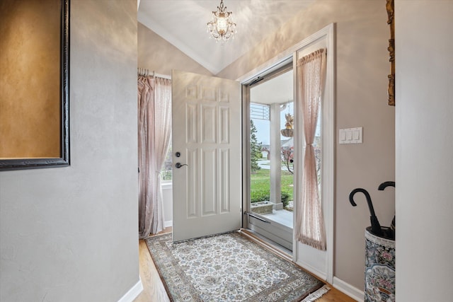 foyer featuring lofted ceiling, hardwood / wood-style floors, and a notable chandelier