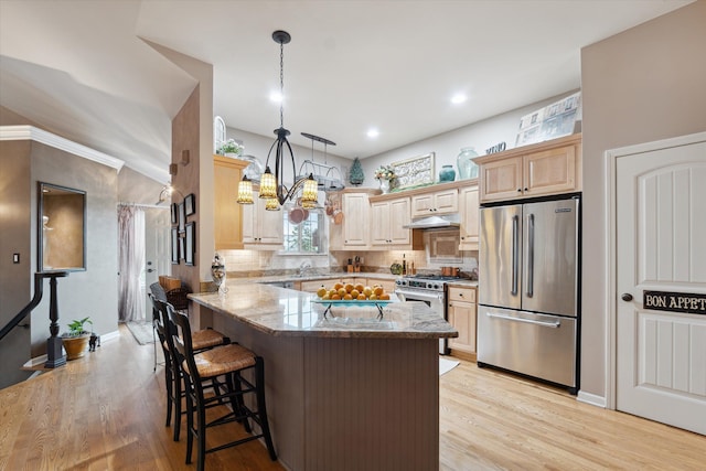 kitchen featuring kitchen peninsula, hanging light fixtures, light stone counters, a kitchen bar, and premium appliances