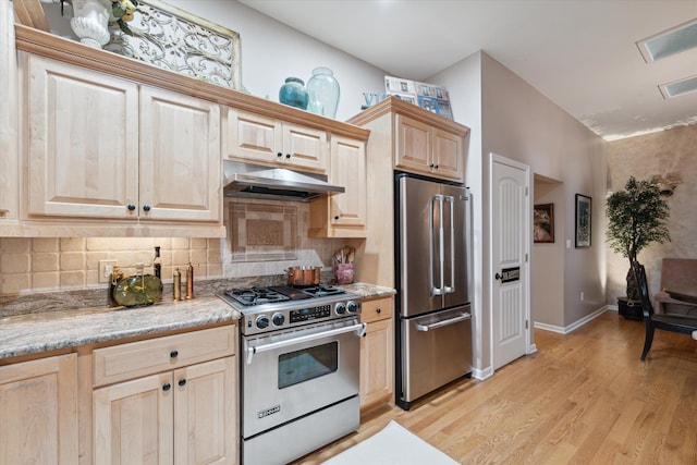 kitchen featuring appliances with stainless steel finishes, tasteful backsplash, light stone countertops, light hardwood / wood-style floors, and light brown cabinets