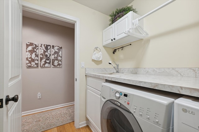 laundry room featuring washer and dryer, sink, cabinets, and light wood-type flooring