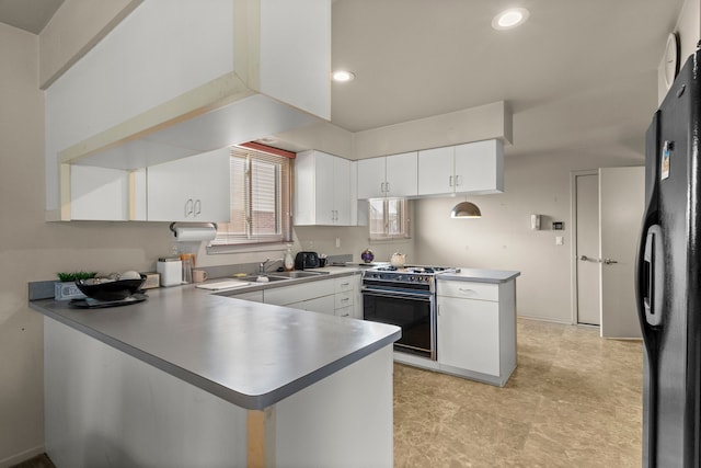 kitchen with sink, black fridge, range, kitchen peninsula, and white cabinets