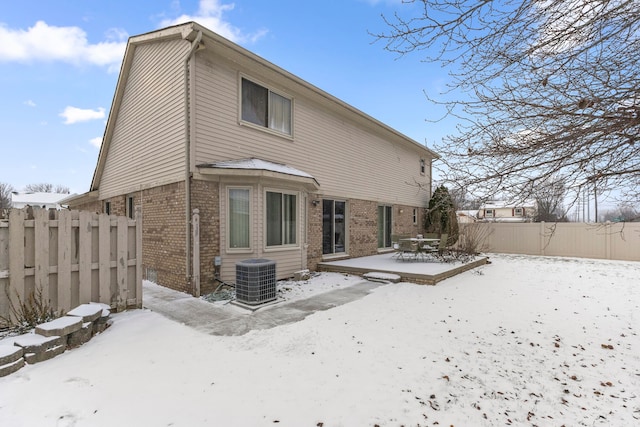 snow covered back of property featuring cooling unit