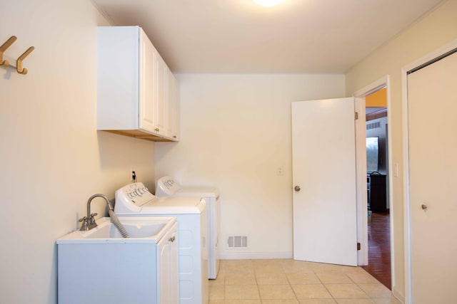 washroom featuring light tile patterned floors, sink, washing machine and dryer, and cabinets