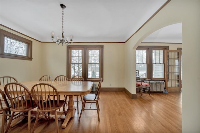 dining area featuring a healthy amount of sunlight, ornamental molding, and light hardwood / wood-style flooring