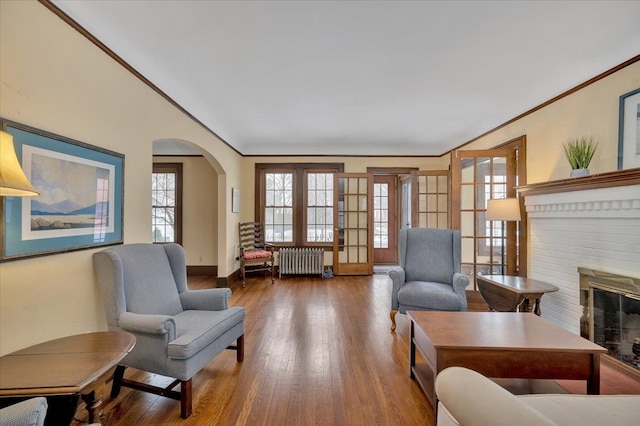 living area featuring hardwood / wood-style flooring, ornamental molding, a fireplace, and radiator