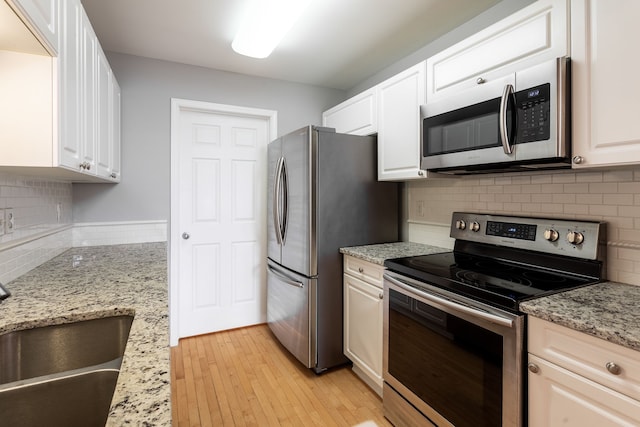 kitchen with light stone counters, stainless steel appliances, and white cabinets