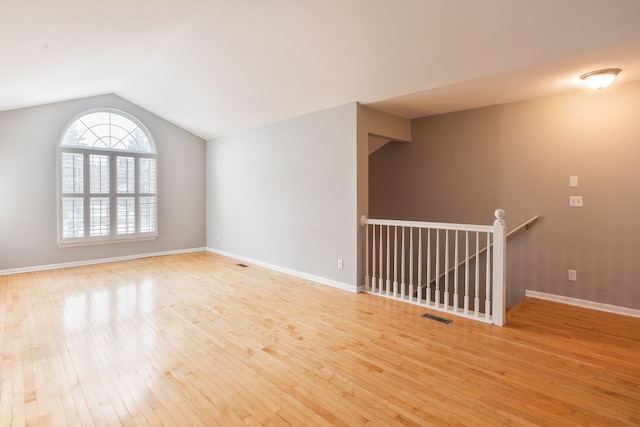 spare room featuring vaulted ceiling and light wood-type flooring